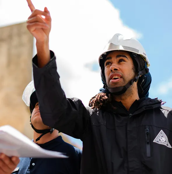 NuReady Health Network construction project discussion with diverse professionals wearing safety gear outdoors.