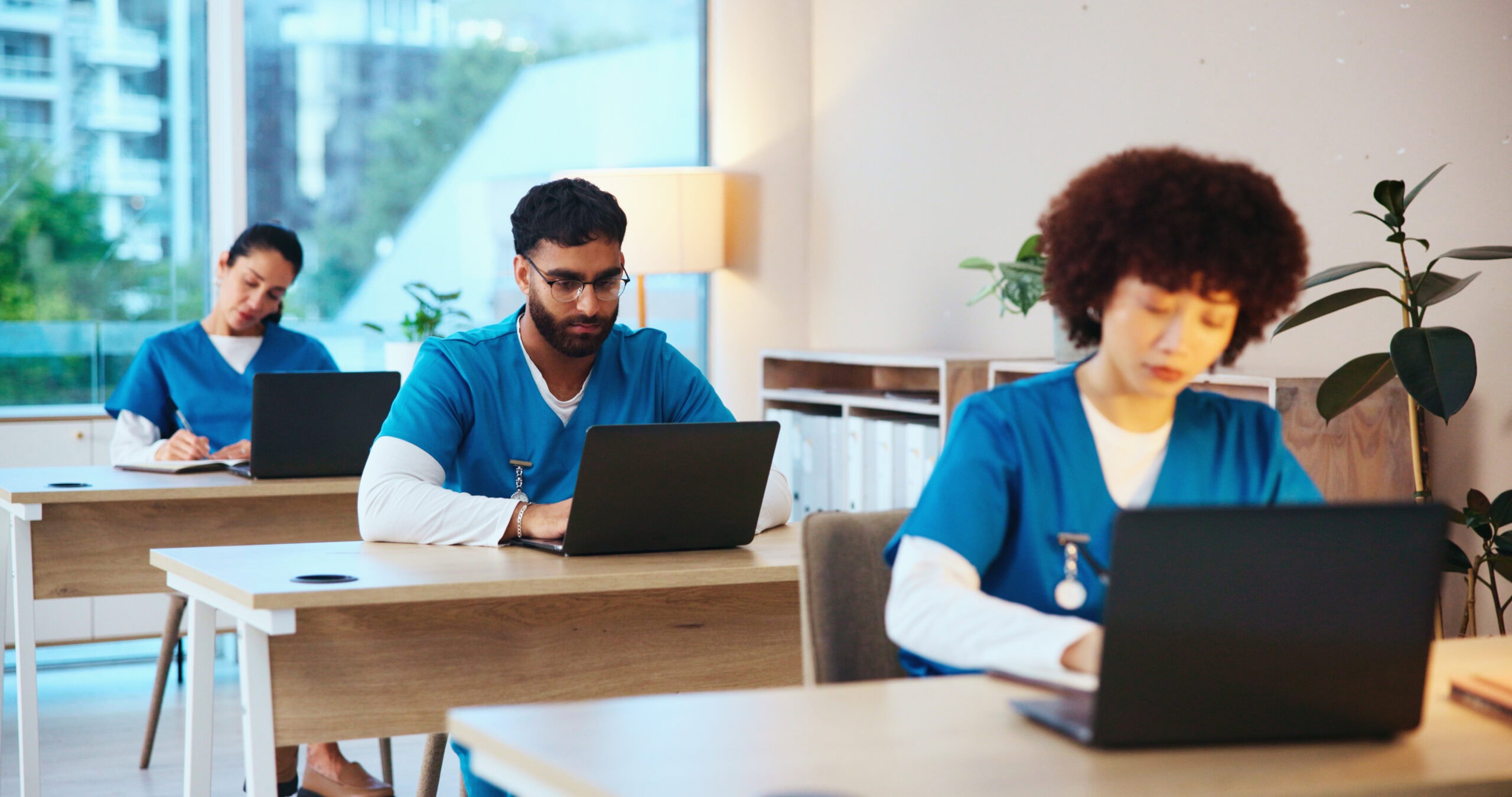 Remote healthcare professionals working on laptops in a modern office for NuReady Health Network.